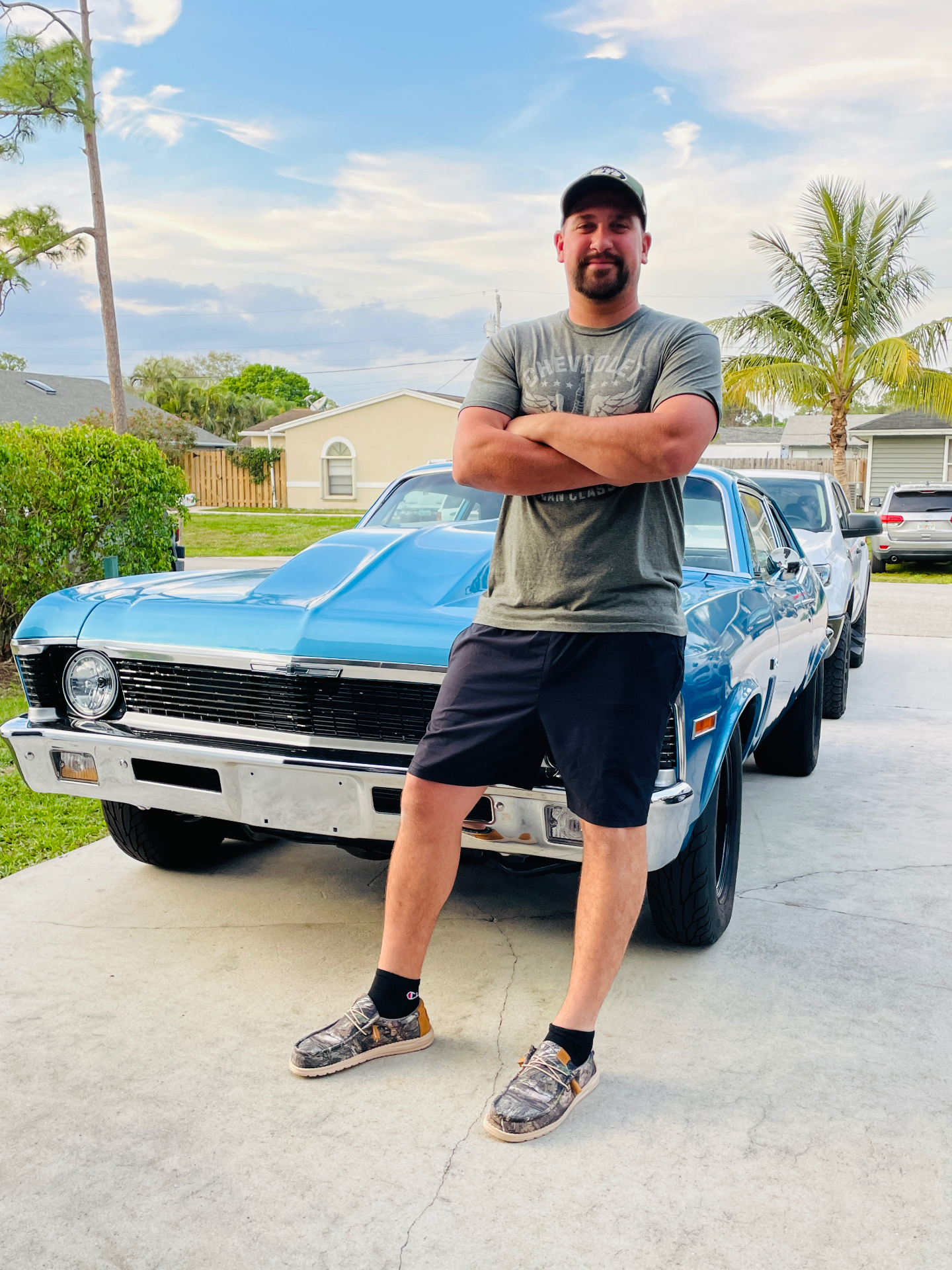 Joe standing beside his blue Chevrolet Nova in a Palm Beach County driveway